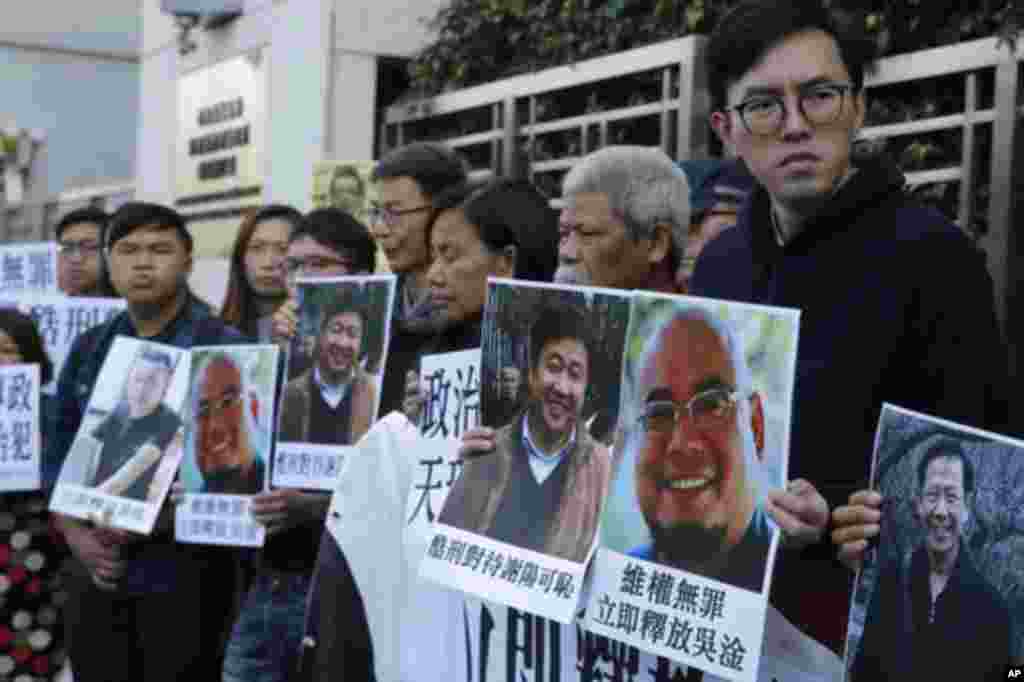 香港民主派活跃分子手持吴淦和谢阳等维权人士的照片在中国中央政府驻港机构中联办外面声援吴淦和谢阳等人(2017年12月27日)。其中古思尧(右二)12月29号因涉嫌去年亵渎国旗被警方预约拘捕。在去年10月的一次抗议中,社民连成员古思尧抬着一个时钟示威道具,上面的中国国旗被倒置,寓意“为共和国送终”。香港媒体报道说,古思尧还被控7月在中联办外焚烧中国国旗。