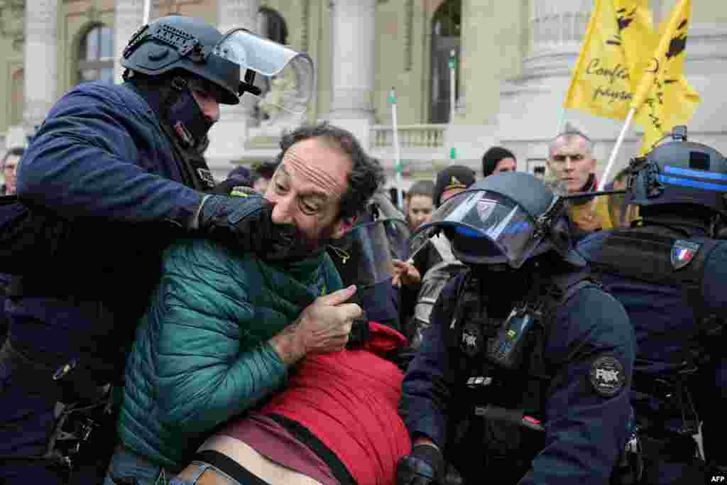 A protester bites the hand of a police officer in riot gear during a demonstration called by the French Farmers' Confederation union to protest against the inauguration of the 64th edition of the European Commodities Exchange at the Grand Palais, in Paris, France.