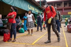 FILE - Travelers queue to buy bus tickets while adhering to social distancing measures and wearing masks to curb the spread of the coronavirus at the Namirembe Bus Park in Kampala, Uganda, June 4, 2020.