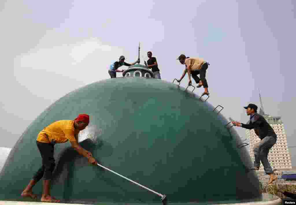 Anak-anak muda membersihkan kubah sebuah masjid di Jakarta sebelum Ramadan dimulai (15/6). (Reuters/Beawiharta)