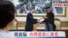 A woman watches a TV screen showing North Korean leader Kim Jong Un, right, and South Korean President Moon Jae-in exchange signed documents in Pyongyang, North Korea, on a news program in Tokyo, Wednesday, Sept. 19, 2018. 