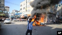 Um palestiniano celebra junto a um carro civil israelita em chamas retirado do kibutz de Kfra Azza em Beit Lahiya, Faixa de Gaza, sábado, 7 de outubro de 2023. Militantes do Hamas levaram a cabo um ataque sem precedentes, com várias frentes, contra Israel ao amanhecer de sábado