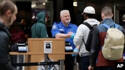 Seorang pekerja keamanan bandara menyerahkan kartu identitas kepada calon penumpang di Bandara Internasional Seattle-Tacoma di Seattle, 25 Januari 2019. 