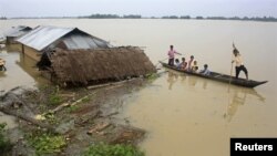 Flood-affected local residents move to safer places on a boat next to their damaged huts after heavy rains at Jajimukh village in the northeastern Indian state of Assam June 27, 2012. Incessant heavy rains in northeast India have caused massive flooding a