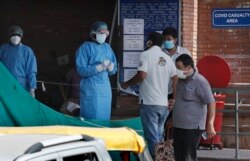 Keluarga pasien menanyakan perkembangan kondisi pasien Covid-19 dari petugas medis di sebuah rumah sakit khusus di New Delhi, India, 10 Jini 2020. (Foto: dok).