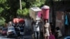 People carry their belongings along a street as they flee their homes from gang violence, in Port-au-Prince, Haiti, Oct. 26, 2024.