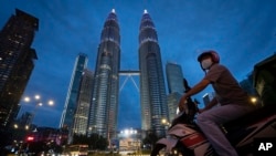 Food delivery rider waits at a traffic junction in front of Twin Towers to deliver food during the movement control order due to the outbreak of the coronavirus disease (COVID-19) in Kuala Lumpur, Malaysia, on Friday, May 1, 2020. Malaysia will…
