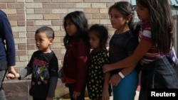 Anak-anak berdiri dalam antrian sebagai keluarga imigran yang memiliki dokumen dilepaskan dari fasilitas penahanan di sebuah halte bus di McAllen, Texas, AS, 22 Juni 2018 (foto: Reuters/Loren Elliott)