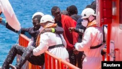 FILE - A migrant, who is part of a group of 58 intercepted aboard a makeshift boat around 100 miles off the coast, is helped by rescue workers upon arriving at Arguineguin port in the Canary Island Gran Canaria, Spain, May 30, 2016.