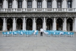 A waiter stands by empty tables outside a restaurant at St Mark's Square, which is usually full of tourists, after Italy's government adopted a decree with new emergency measures to contain the coronavirus, in Venice, Italy, March 5, 2020.