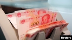 FILE PHOTO: Chinese 100 yuan banknotes are seen in a counting machine while a clerk counts them at a branch of a commercial bank in Beijing, China, March 30, 2016. REUTERS/Kim Kyung-Hoon/File Photo
