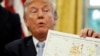 FILE - President Donald Trump holds up a map as he speaks about Harvey in the Oval Office of the White House, Sept. 1, 2017, in Washington. 