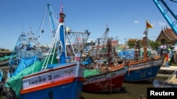 Seorang nelayan duduk saat kapal-kapal penangkap ikan terlihat berlabuh setelah operasi penangkapan ikan dihentikan di sebuah pelabuhan di Provinsi Samut Sakhon, Thailand. (Foto: Reuters)