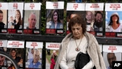 Seorang perempuan di Tel Aviv, Israel berhenti sejenak dekat poster-poster warga Israel yang masih disandera Hamas di Jalur Gaza ketika Kabinet keamanan Israel sedang rapat untuk membahas gencatan senjata dengan Hamas, Jumat, 17 Januari 2025. (Foto: Maya Alleruzzo/AP Photo)