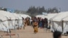 Una niña camina mientras carga a un niño frente a las tiendas de campaña erigidas para los desplazados internos después de un terremoto, en la ciudad rebelde de Jandaris, Siria, el 4 de marzo de 2023.