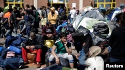 Pengungsi dan migran duduk di dekat barang-barang bawaan mereka, menunggu kendaraan yang akan membawa mereka ke tempat yang disediakan untuk akomodasi mereka di port of Piraeus, dekat Athena, Yunani (31/3).