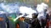 Seorang polisi menembakkan gas air mata saat bentrok dengan para mahasiswa yang berunjuk rasa di Surabaya, Jawa Timur, 8 Oktober 2020. (Foto: AP)
