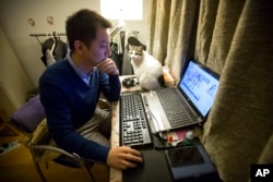 FILE - Office worker Zhai, 28, who asked that only his last name be used, watches a live web stream from a Korean web performer on his computer at his apartment in Beijing.