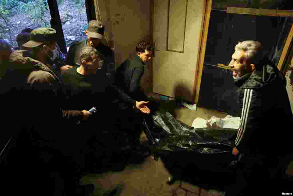 Men carry a body, believed to be of a prisoner from Sednaya prison, according to forensic official Zaher al-Taqesh, at the Al Mojtahed hospital, in Damascus, Syria.
