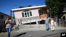 Residents survey damage where a home partially collapsed after an earthquake hit Guanica, Puerto Rico, Jan. 6, 2020.