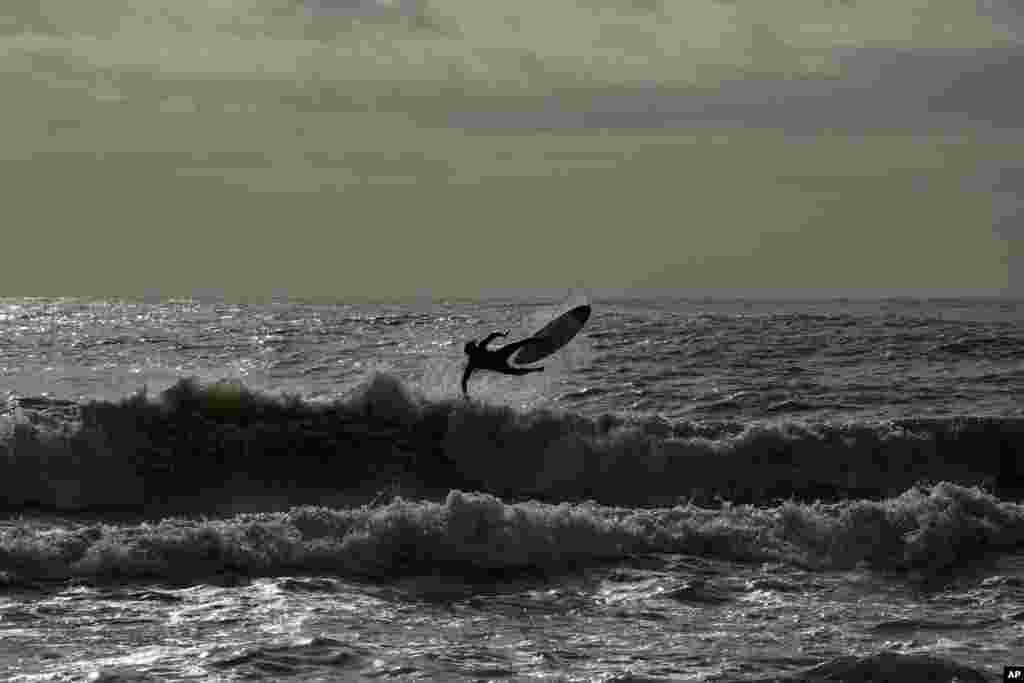 A surfer rides a wave at Rome's Ostia beach, Italy.