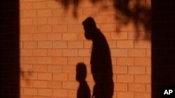 FILE - The shadows of a man and child are cast on a wall in Davie, Florida, Oct. 9, 2020. Poverty in the United States surged in 2022, particularly among children, after social support programs put in place during the coronavirus pandemic expired, according Census Bureau data. 