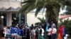 Migrants line up to receive sanitizers outside a hotel used as a refugee shelter, after authorities found several cases of the novel coronavirus and put the area under quarantine, in Kranidi, Greece, April 21, 2020.