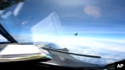 Sebuah pesawat tempur J-16 China terbang dengan agresif di dekat pesawat RC-135 AS yang terbang di wilayah udara internasional di atas Laut China Selatan, Jumat, 26 Mei 2023. (Angkatan Laut AS via AP)