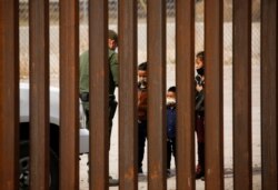 Para migran ditahan oleh Dinas Patroli Perbatasan AS setelah menyeberang Sungai Rio Bravo untuk menyerahkan diri dan meminta suaka di El Paso, Texas, 29 Maret 2021.