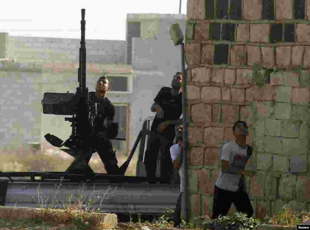 A Free Syrian Army fighter fires an anti-aircraft gun as a Syrian Air Force fighter bomber fires rockets during an air strike in the village of Tel Rafat, some 37 km (23 miles) north of Aleppo, August 9, 2012.