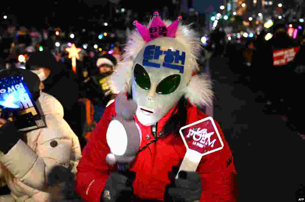 A man wearing a mask with the word "Impeachment" written on it waves light sticks as he takes part in a protest calling for the ouster of South Korea President Yoon Suk Yeol, near the National Assembly in Seoul.