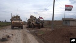 In this frame grab from video, an American military convoy is seen in the village of Khirbet Ammu, east of Qamishli city, Syria, Wednesday, Feb. 12, 2020. Syrian media and activists say a Syrian was killed and another wounded in a rare clash between…