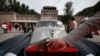 FILE - A man places his hand near the logo of a Rolls Royce at the Shuiguan Great Wall on the outskirts of Beijing, China, Sept. 18, 2011. A new law now tries to coordinate charitable giving by country's richest.