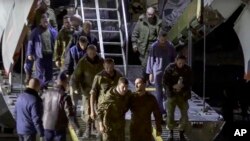 Sekelompok tahanan perang Rusia meninggalkan pesawat militer Rusia setelah mereka dibebaskan. (Foto: via AP)