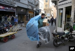 FILE - A man carries car parts at a market in downtown Tehran, Iran, Oct. 9, 2017. Iranians hope the lifting of most international sanctions under Tehran’s landmark 2015 nuclear deal with the West will revive their country's long-suffering economy.
