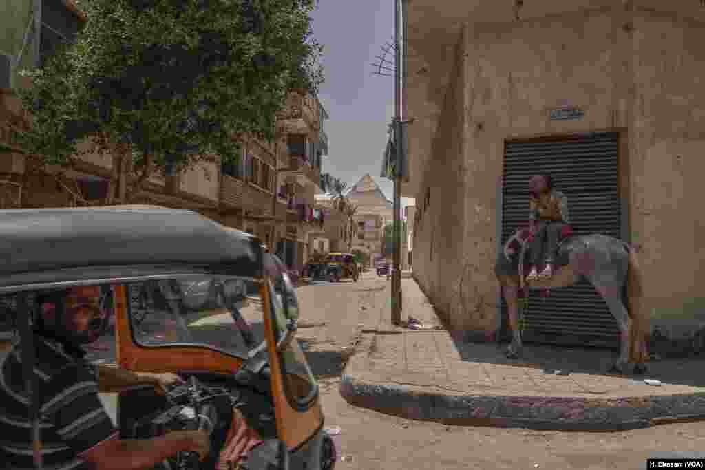 Egypt’s ancient pyramids stand as timeless examples of the ultimate in construction design and planning, towering over a much different scenario in Giza’s Nazlet el-Semman neighborhood. Narrow streets and lack of urban planning mean no access for public transportation. Residents rely on three-wheeled motorcycles and animals.