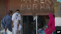 A Kashmiri man tries on a pair of shoes outside a shop in Srinagar, Indian controlled Kashmir, May 16, 2020.