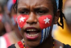 Seorang mahasiswa Papua dengan wajah dicat bendera "Bintang Kejora" meneriakkan slogan-slogan dalam unjuk rasa di depan Istana Kepresidenan di Jakarta, 28 Agustus 2019.