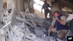 This image taken Sept. 30, 2015 posted on the Twitter account of Syria Civil Defence, also known as the White Helmets, a volunteer search and rescue group, shows the aftermath of an airstrike in Talbiseh, Syria.