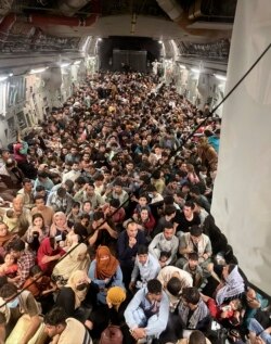 Afghan citizens pack inside a U.S. Air Force C-17 Globemaster III, as they are transported from Hamid Karzai International Airport in Afghanistan, Sunday, Aug. 15, 2021. The Taliban on Sunday swept into Kabul, the Afghan capital, after capturing most of