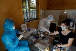 Medical specialists collect blood sample from a woman who has returned after travelling to Da Nang, at a rapid testing center for COVID-19 outside Hanoi, Vietnam, July 30, 2020.
