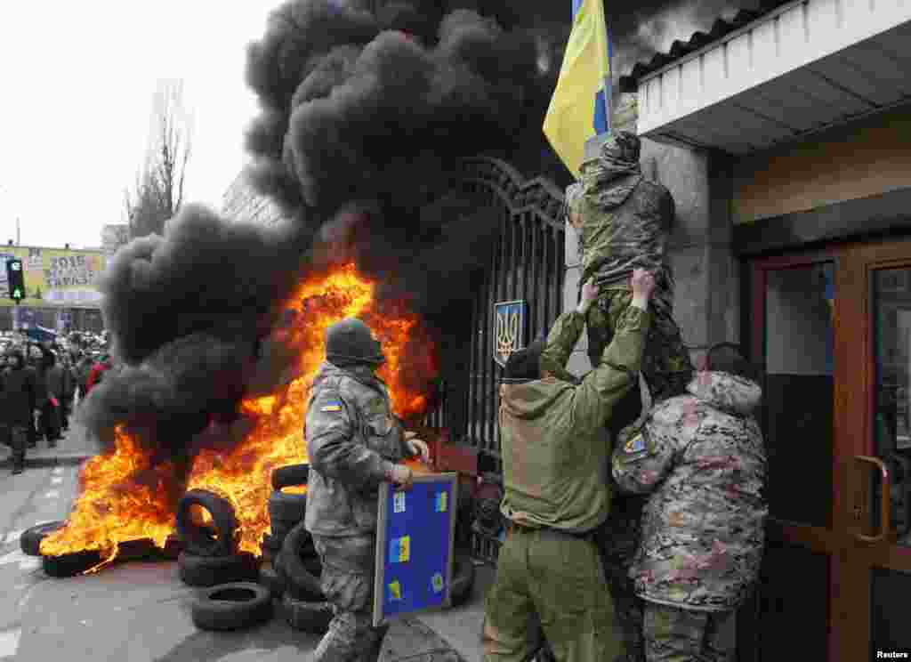 Servicemen from the battalion "Aydar" remove a Ukrainian flag from the Ukraine's Defense Ministry during a protest against the disbanding of the battalion, in Kyiv, Feb. 2, 2015.