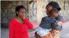Pendiri sekolah menengah Serene Haven, Elizabeth Wanjiru berbicara dengan Josephine Wanjiru, 19, yang menggendong anaknya di luar asrama di sekolah menengah Serene Haven. (Foto: REUTERS/Monicah Mwangi)