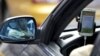 FILE - A taxi driver is reflected in a side mirror as he uses the Didi Chuxing car-hailing application in Beijing, China, Sept. 22, 2015. 