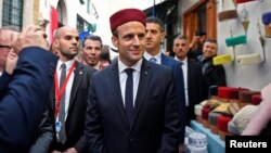 Presiden Perancis Emmanuel Macron mengenakan fez (kopiah khas Tunisia) pada kunjungannya ke Tunis, hari Kamis (1/2). 