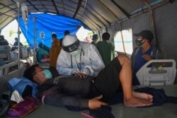 Seorang pria yang cedera akibat gempa 6,2 magnitudo yang terjadi pada 15 Januari sedang dirawat di tenda darurat di luar rumah sakit karena khawatir gempa susulan, di Kota Mamuju, Minggu, 17 Januari 2021. (Foto: Adek Berry/AFP)