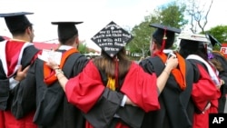 FILE - In this May 15, 2016, photo, students embrace as they arrive for the Rutgers graduation ceremonies in Piscataway, N.J. More Americans are getting buried by student debt, causing delays in home ownership, limiting how much people can save and leavi