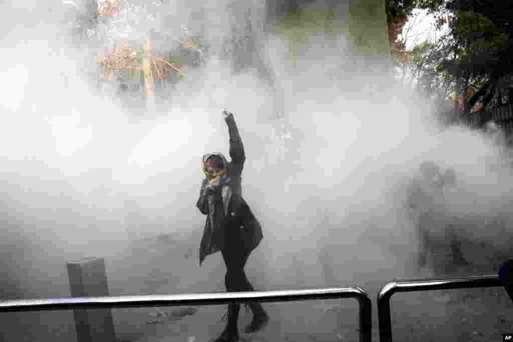 A university student attends a protest inside Tehran University while a smoke grenade is thrown by anti-riot Iranian police, in Tehran, Iran, Dec. 30, 2017. A wave of spontaneous protests over Iran's weak economy swept into Tehran Saturday, with college students and others chanting against the government just hours after hard-liners held their own rally in support of the clerical establishment.