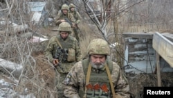 Sejumlah anggota pasukan keamanan Ukraina berjalan di perbatasan yang memisahkan dengan para pemberontak pro Rusia dekat Donetsk, Ukraina, 11 April 2021.