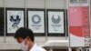 Seorang pria mengenakan masker berjalan melewati poster Olimpiade Tokyo di Tokyo, Jepang, 7 JUni 2021. (AP Photo/Koji Sasahara)